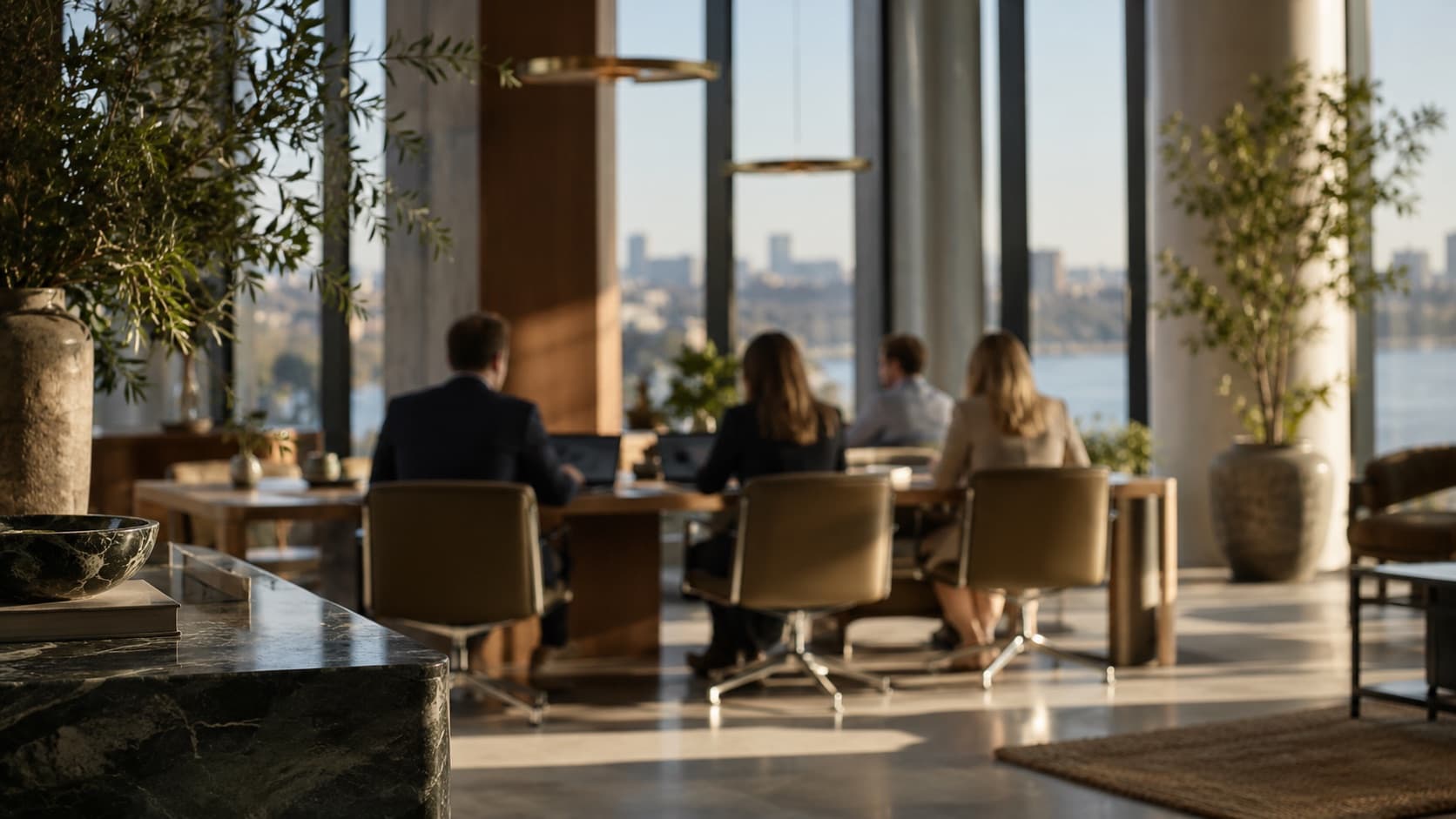Colleagues working at a long table near tall windows